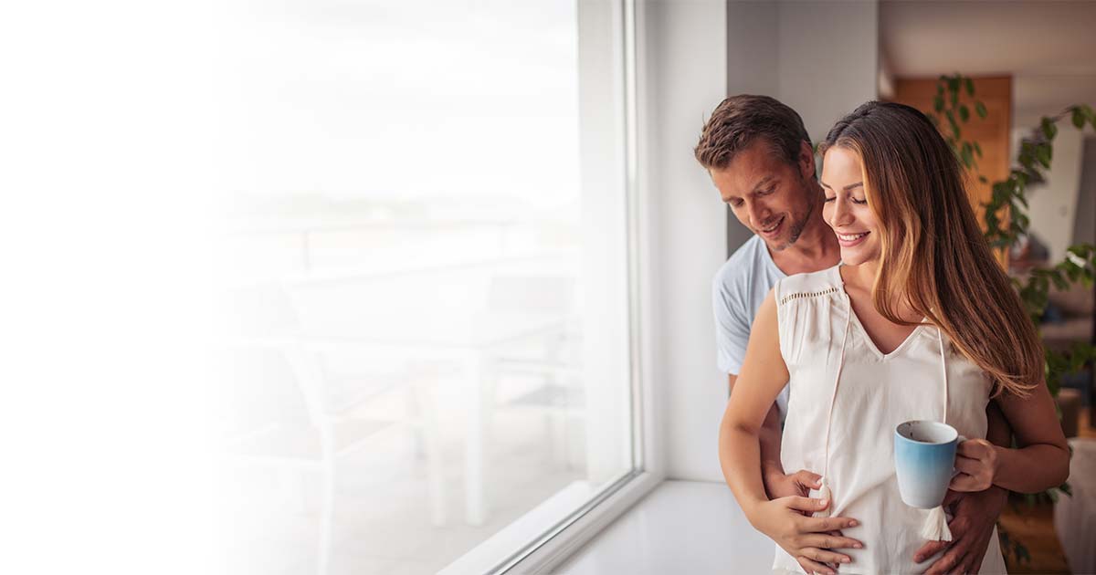 Lifestyle image of a pregnant couple hugging