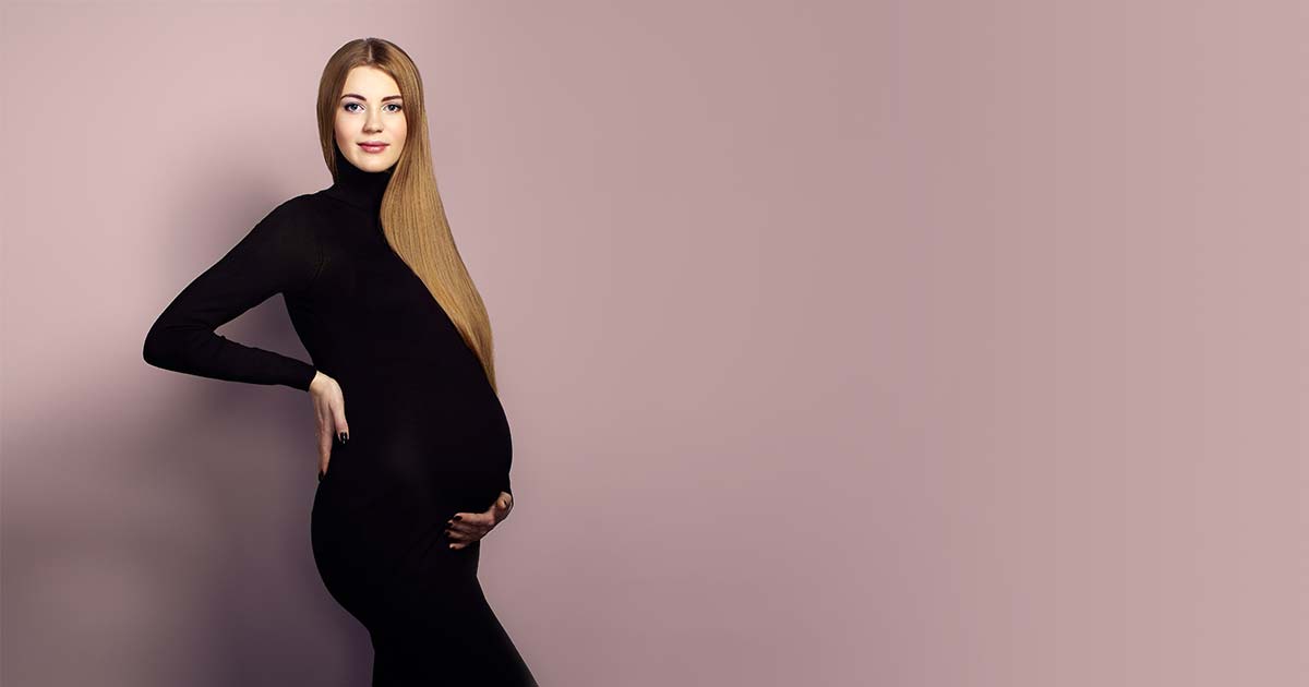 Pregnant woman in a black bodysuit posing for a maternity photo