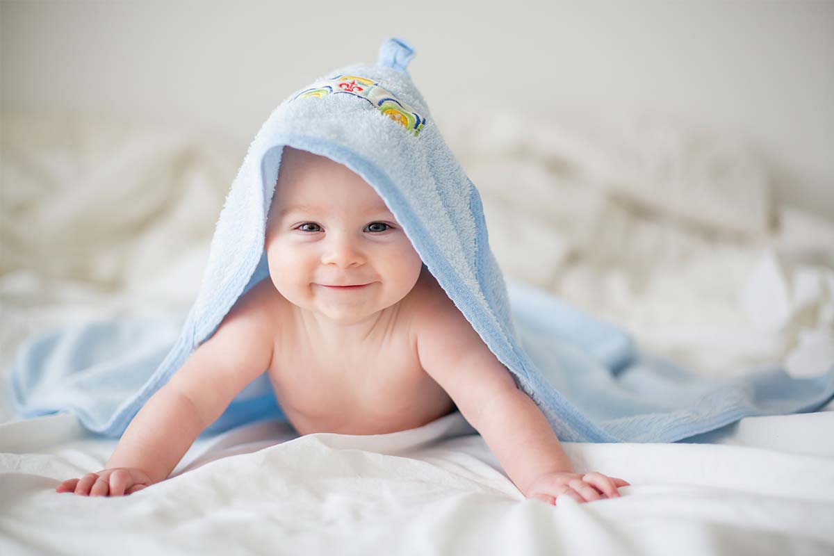 A smiling newborn baby covered with a blanket