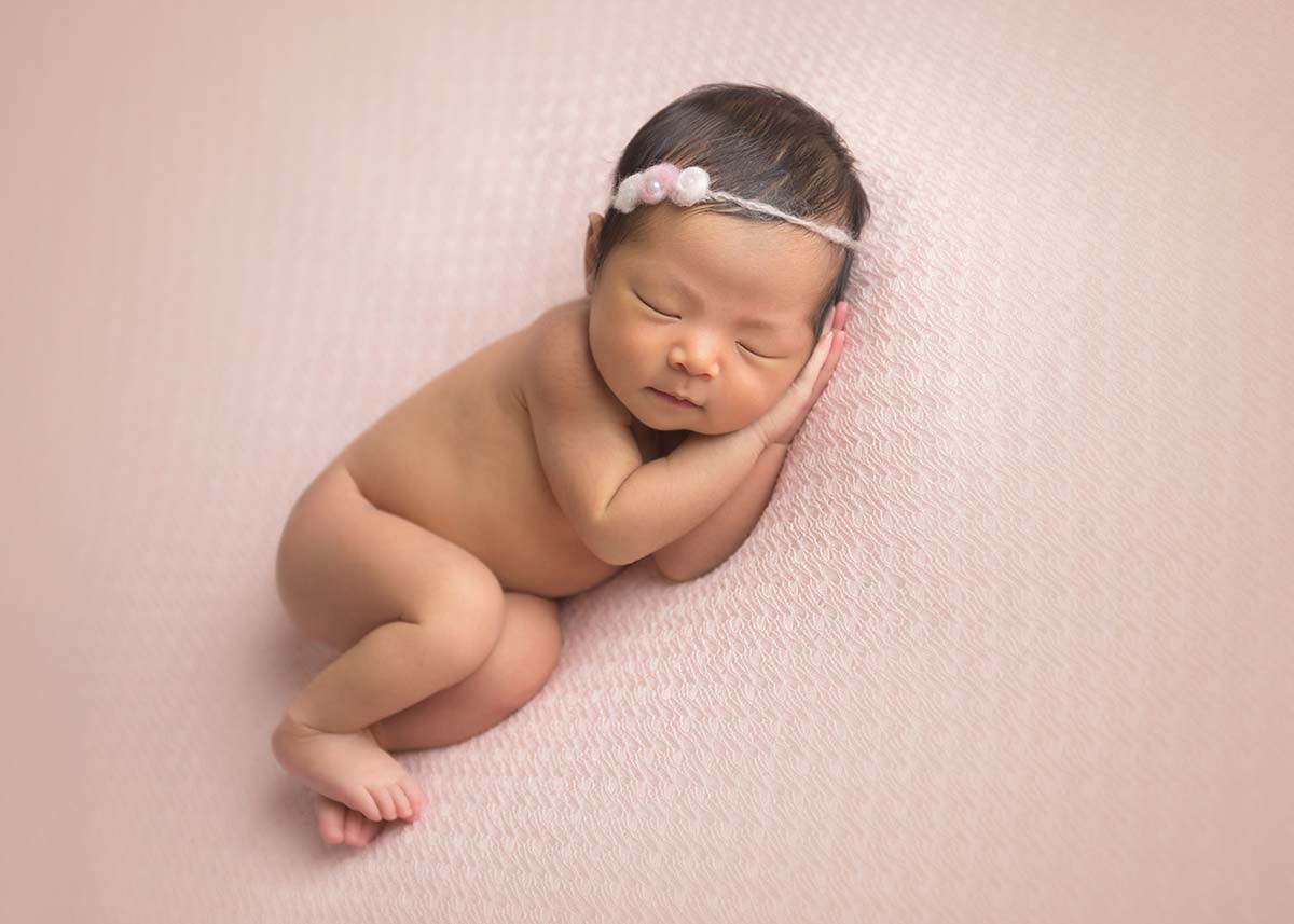Beautiful newborn photo of a girl sleeping happily on a pink blanket at a NYC photo studio