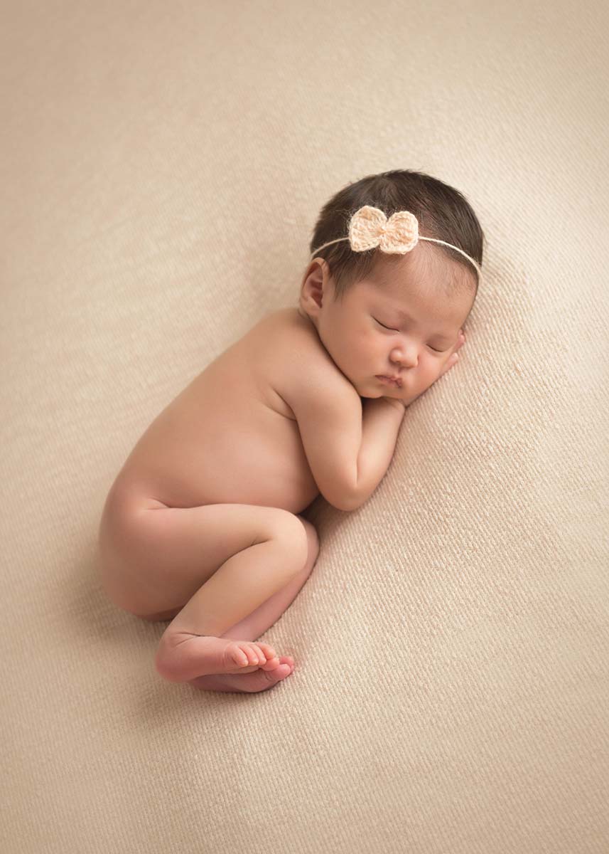 Infant girl with a headband sleeping on her side