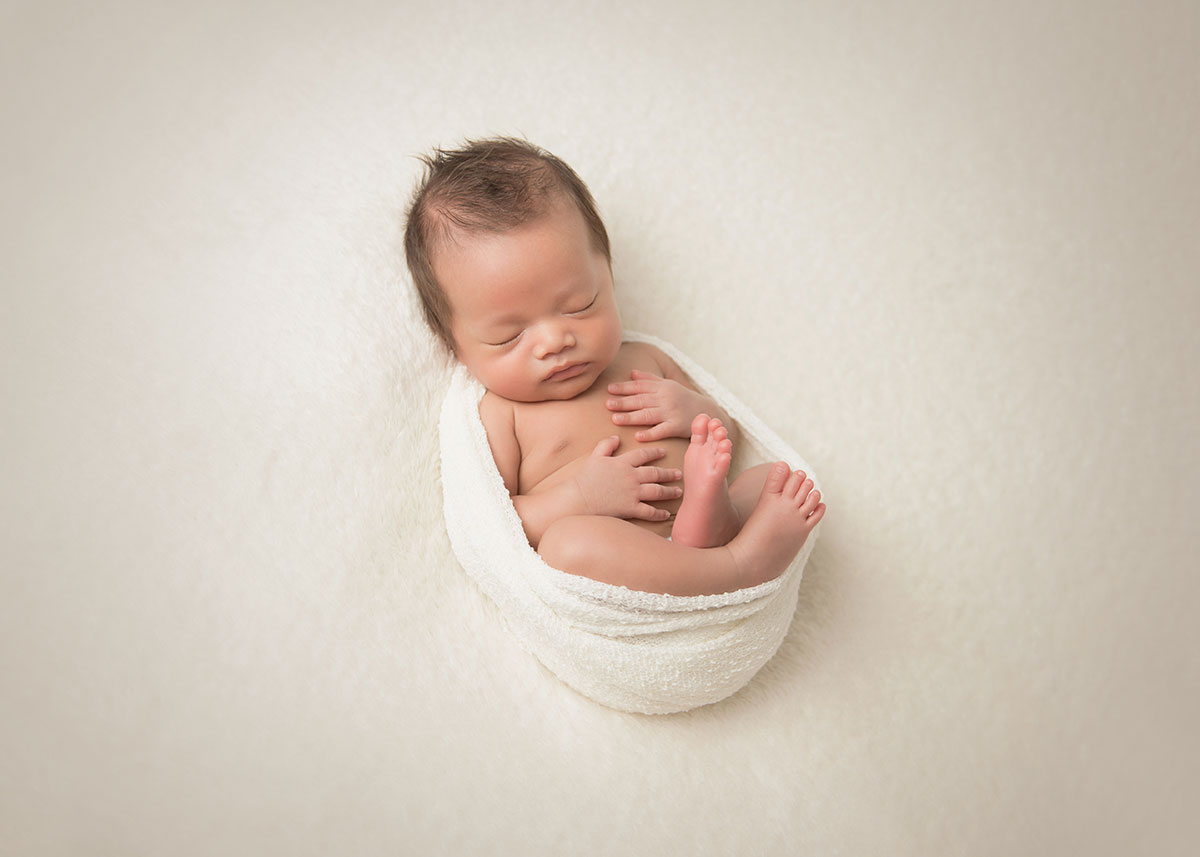 Beautiful infant wrapped in a swaddle posing for a newborn portrait