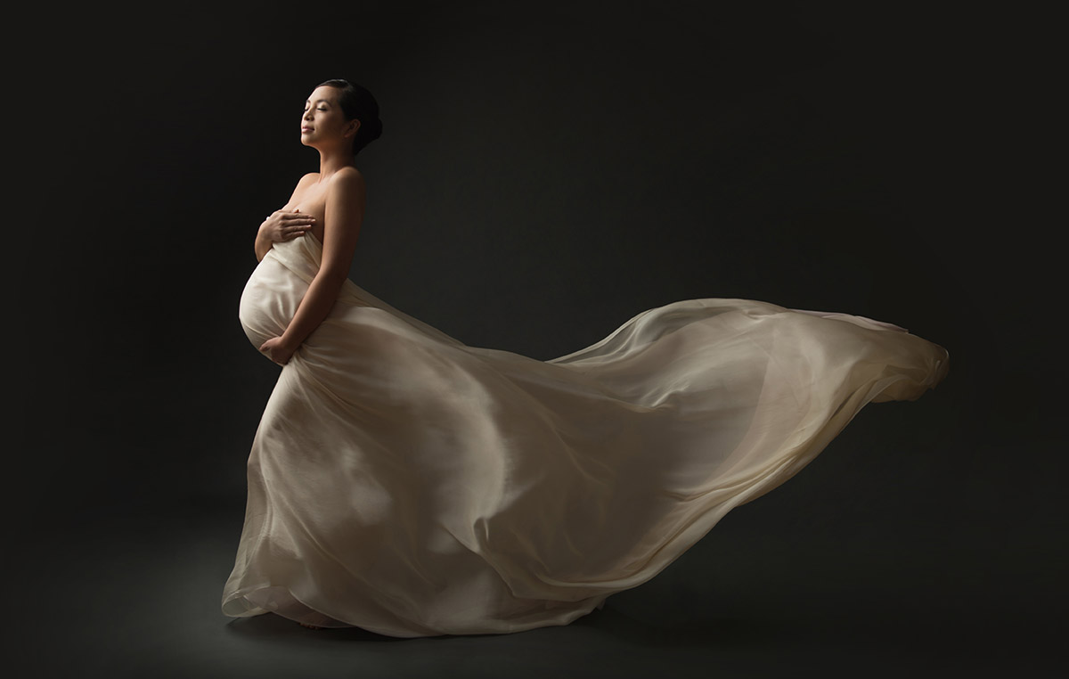 Artistic portrait of a pregnant woman wearing a long flowing fabric