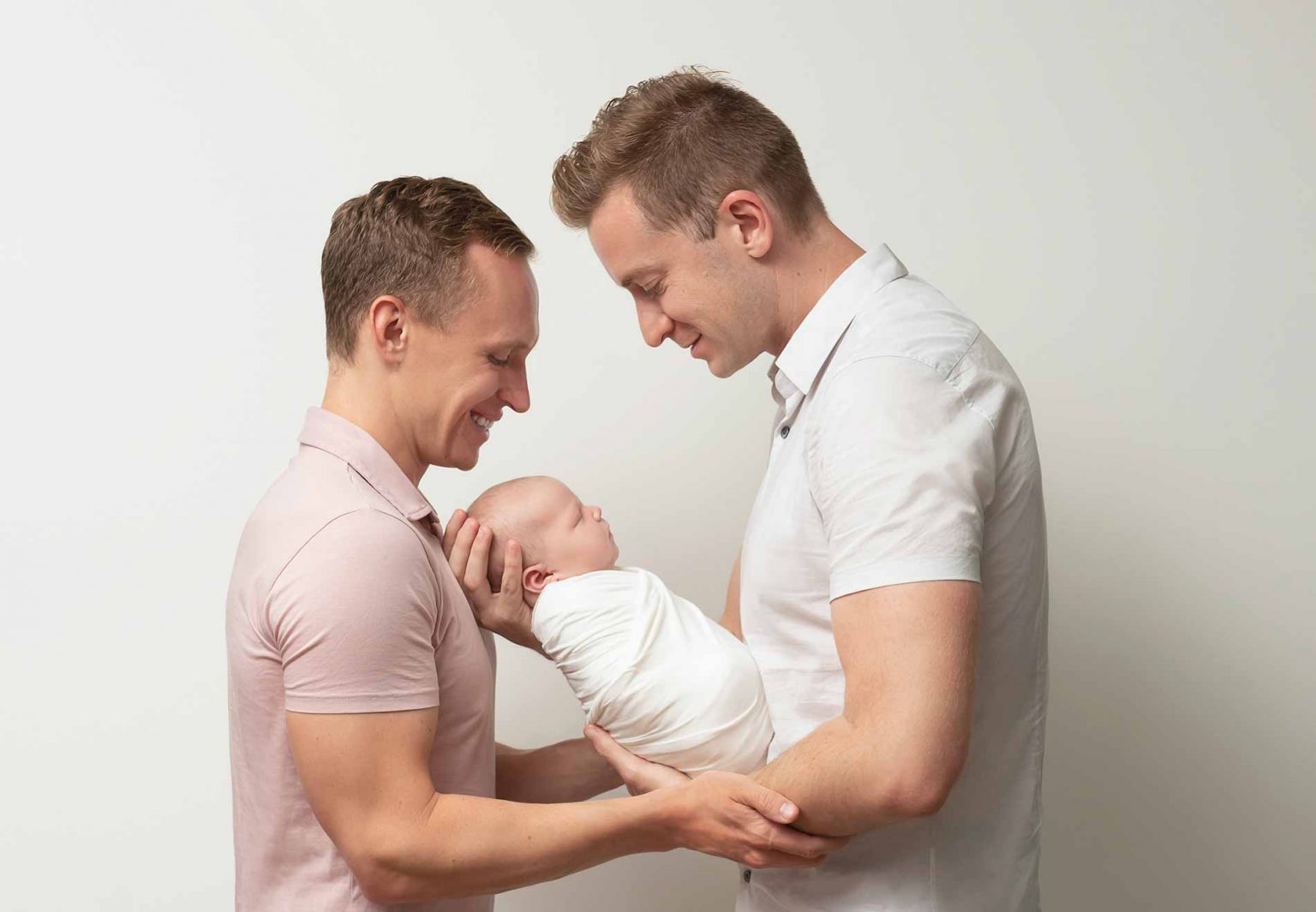 Parents posing for a family portrait with their newborn baby
