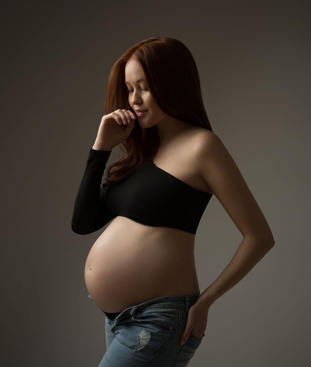 Pregnant model with red hair wearing jeans and a black crop top