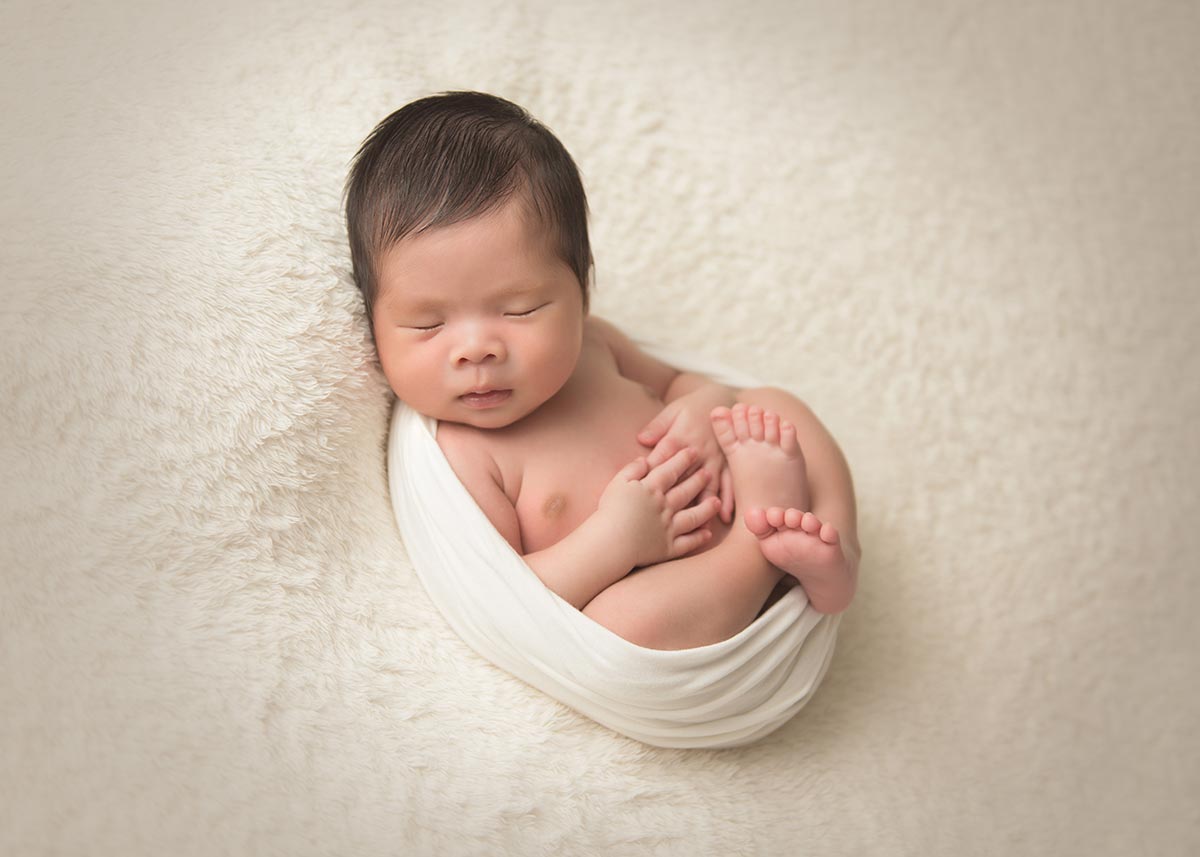 NYC Newborn Photographer captures a beautiful portrait of a sleeping infant in a swaddle