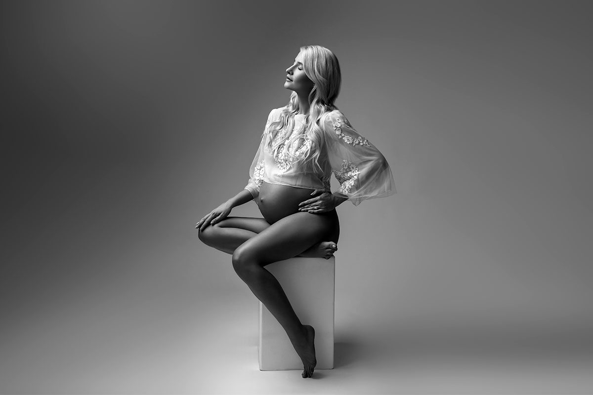 Black and white image of a pregnant woman in a photo studio