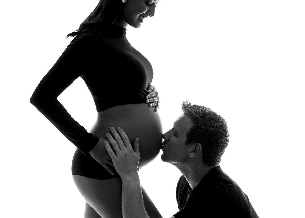 Joyous father kissing his wife's pregnant belly