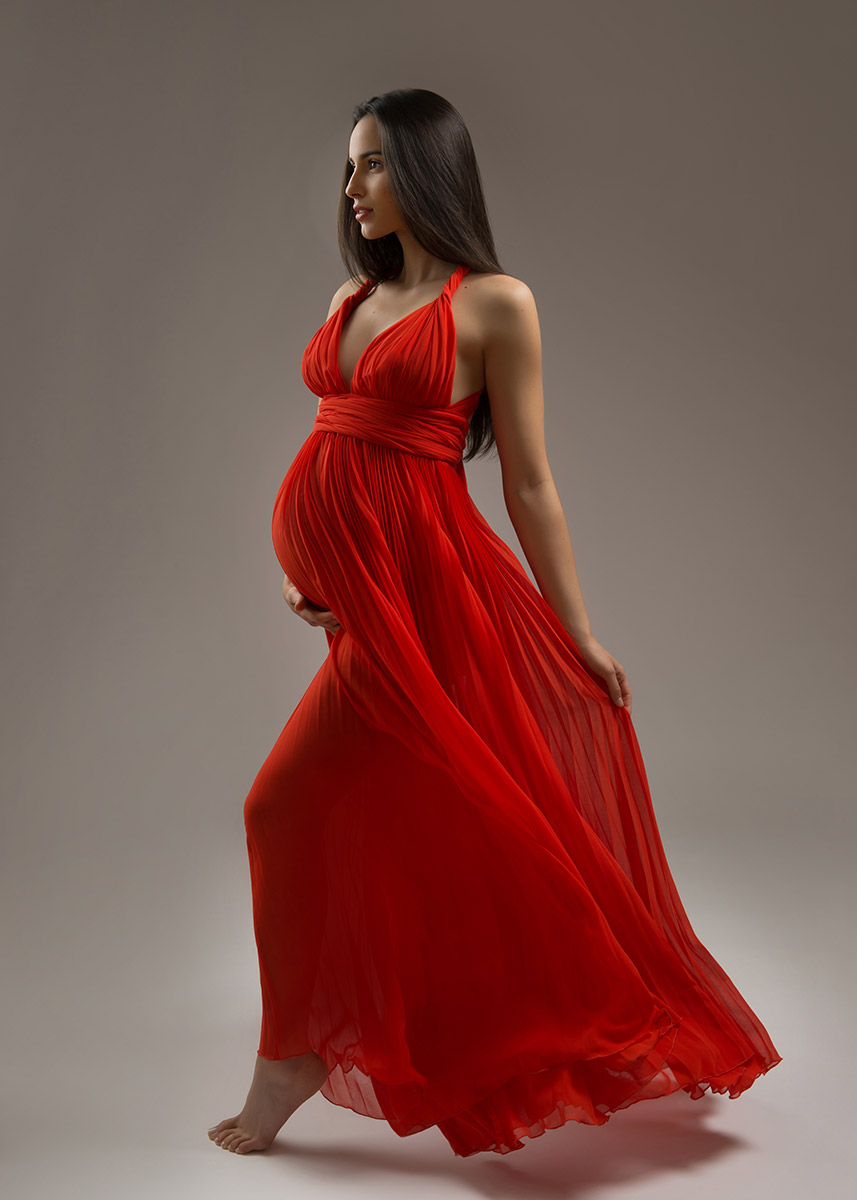 Beautiful woman showing off her pregnant belly and red dress