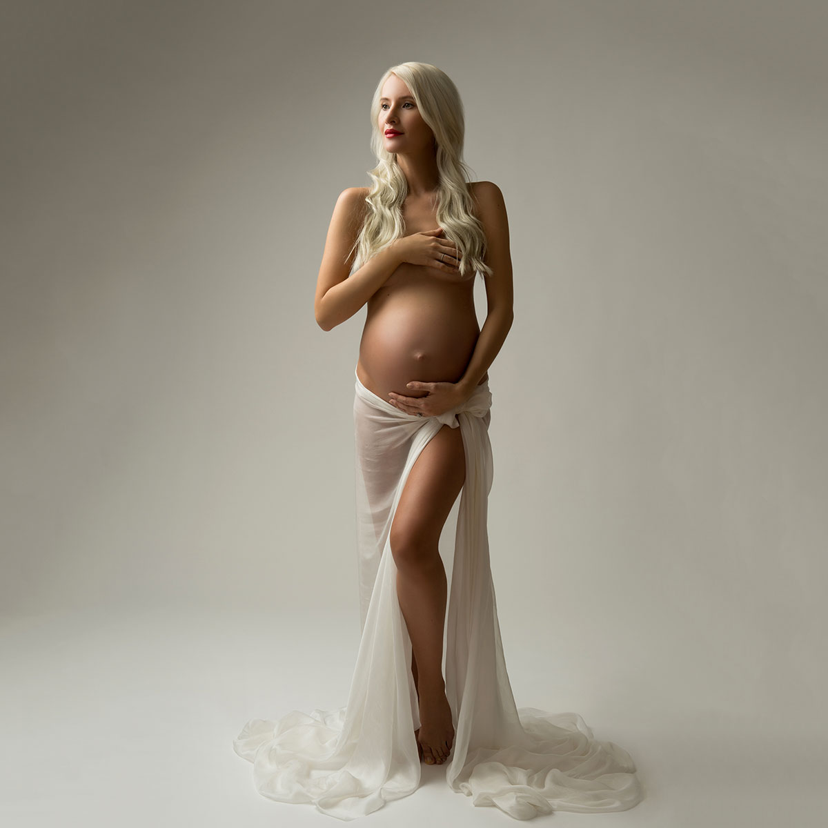 Blonde woman in studio posing for maternity portrait