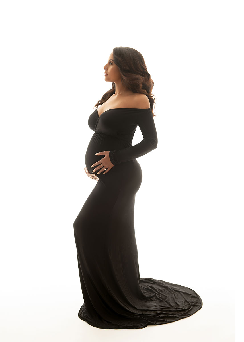 Elegant black gown worn by a pregnant woman in studio