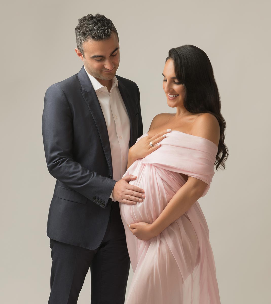 Husband in a suit posing for a pregnancy photo with his wife