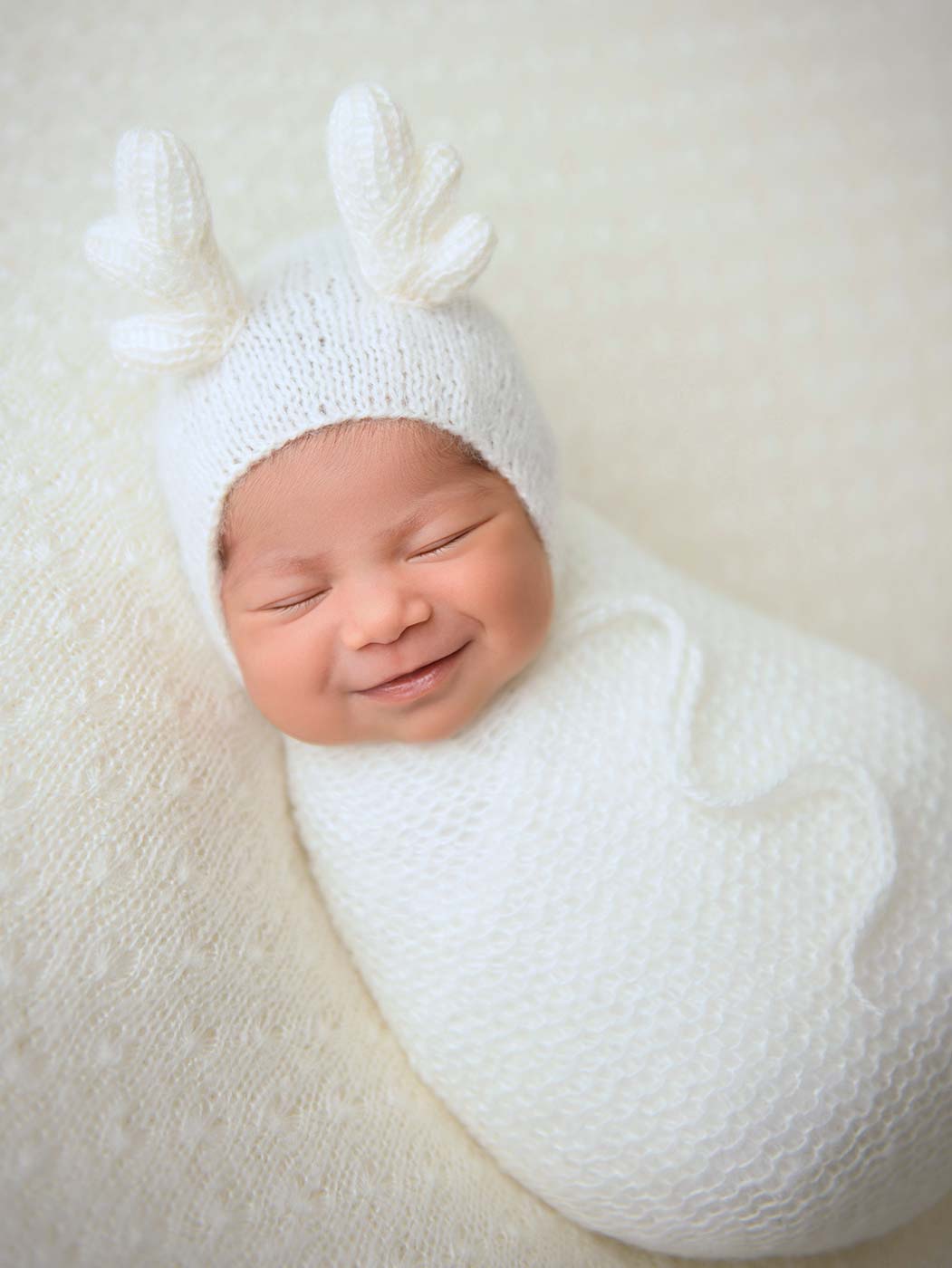baby newborn with holiday reindeer antlers bonnet smiling