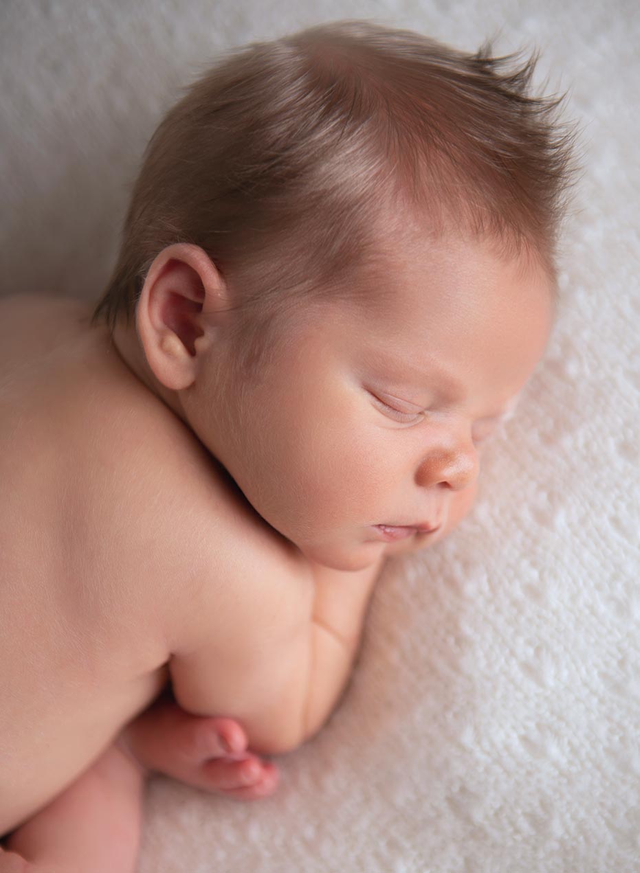 cute closeup newborn portrait of infant sleeping in curled up pose
