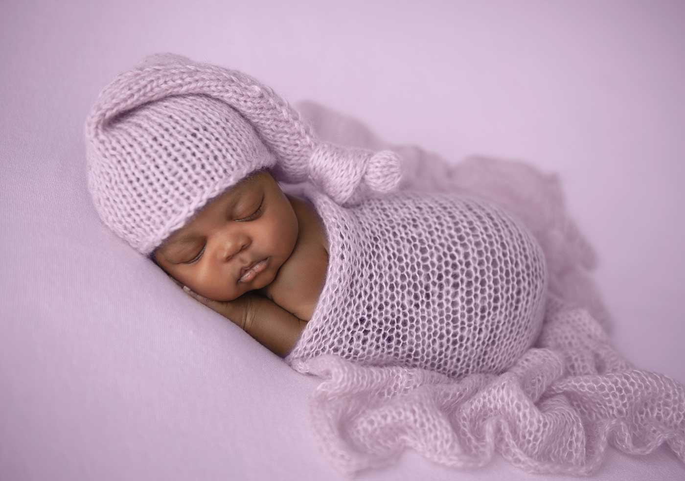 Infant sleeping peacefully on a purple blanket