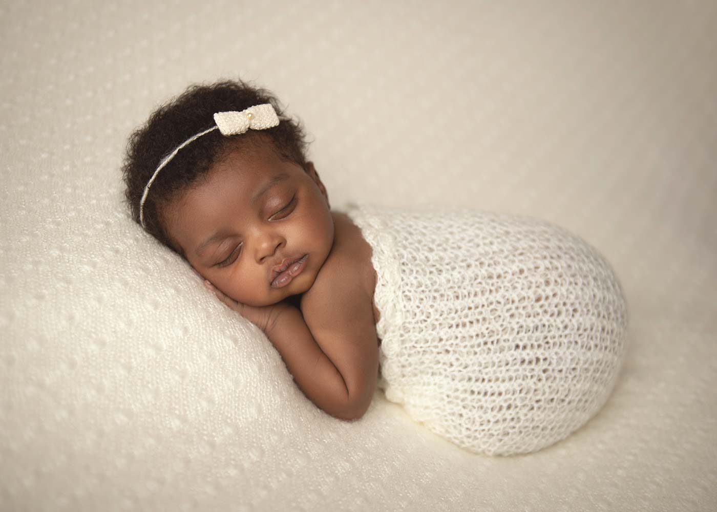 Baby girl wrapped in a knit blanket smiling for a NYC baby photographer
