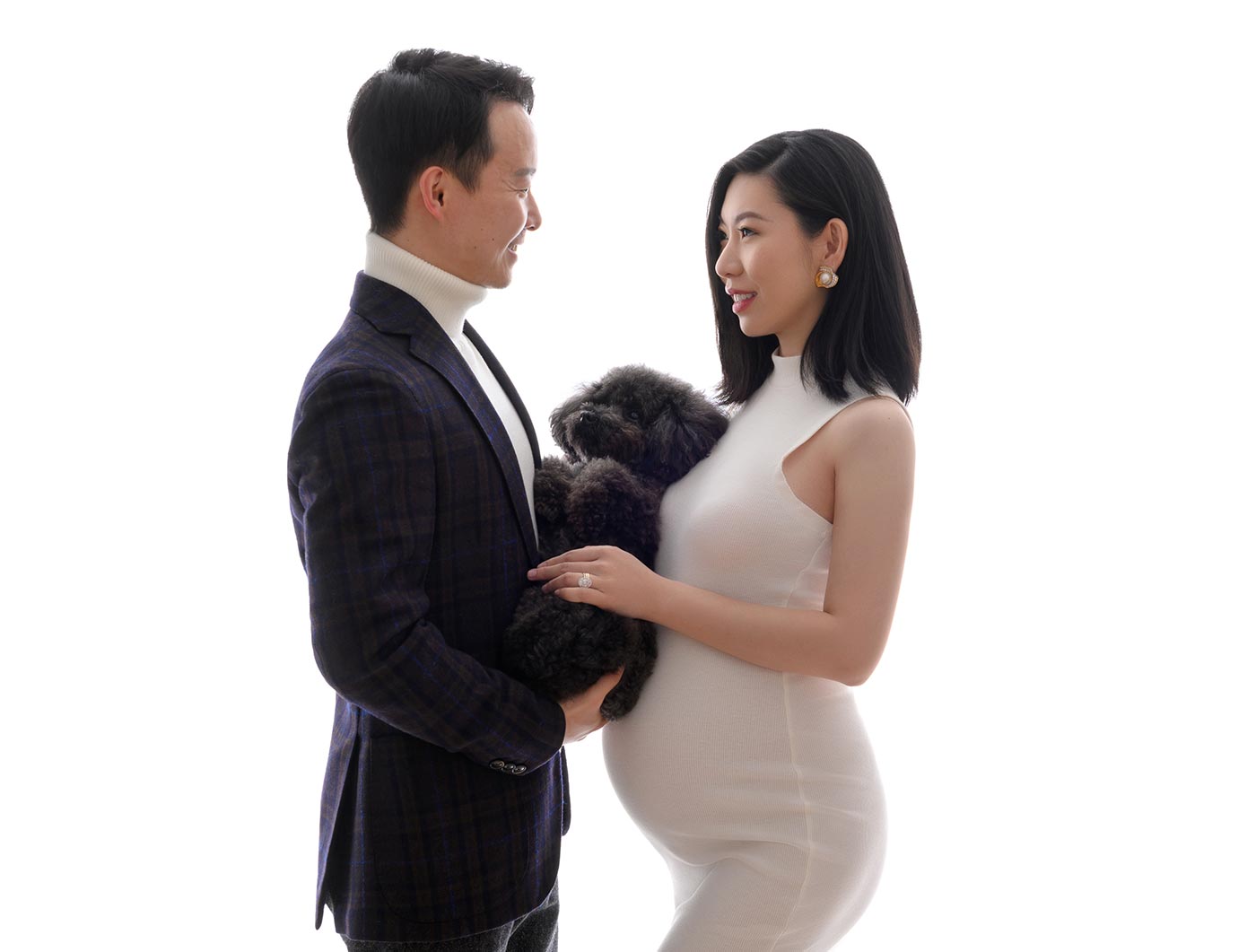 Married couple posing for a pregnancy photo along with their pet