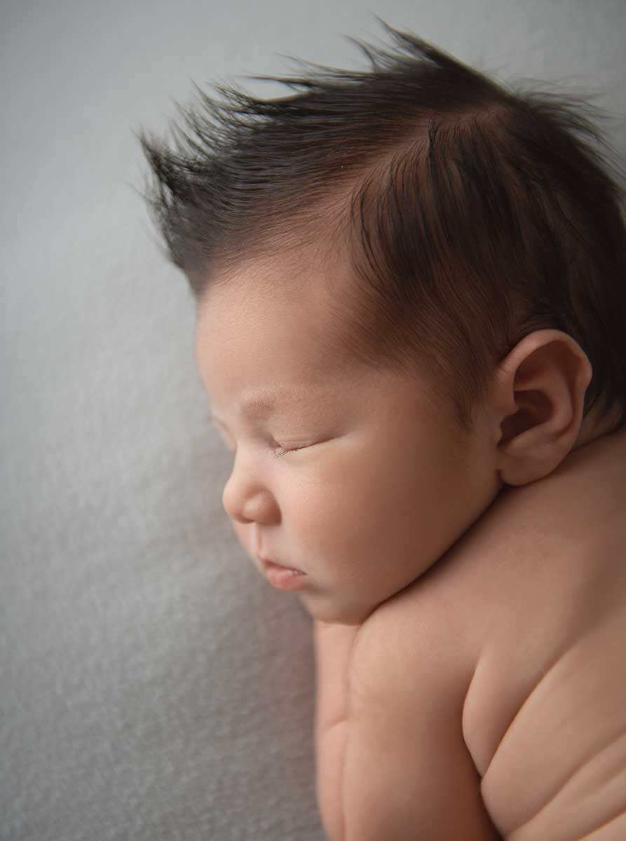 Newborn baby with a cute mohawk being photographed at a photo studio in NYC