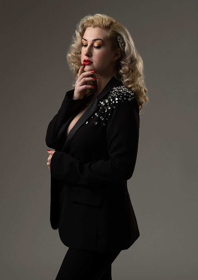 studio beauty photoshoot with woman wearing rhinestone black blazer and glam makeup