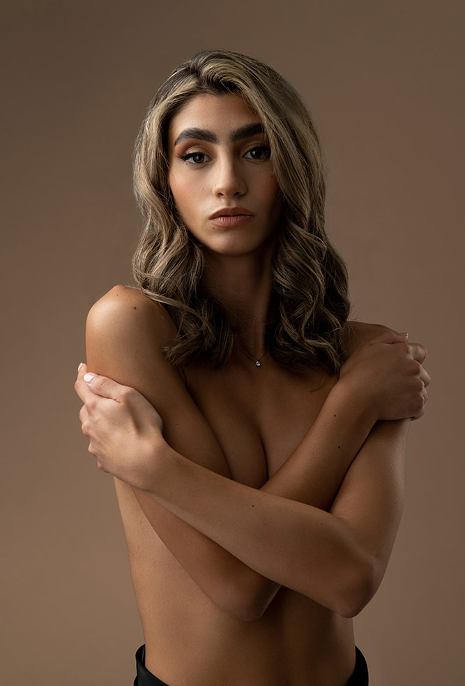 topless nude portrait of beautiful woman on beige backdrop
