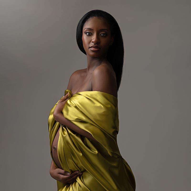 Green silk fabric draped over a pregnant woman in this beautiful maternity photo
