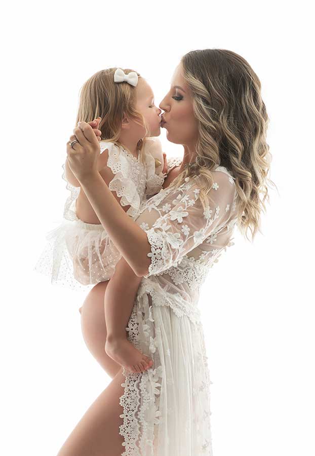 Mother wearing embroideried dress while kissing her daughter