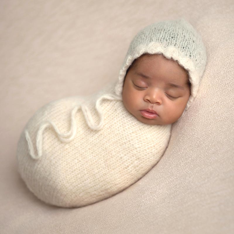 Newborn girl swaddled in a knit wrap