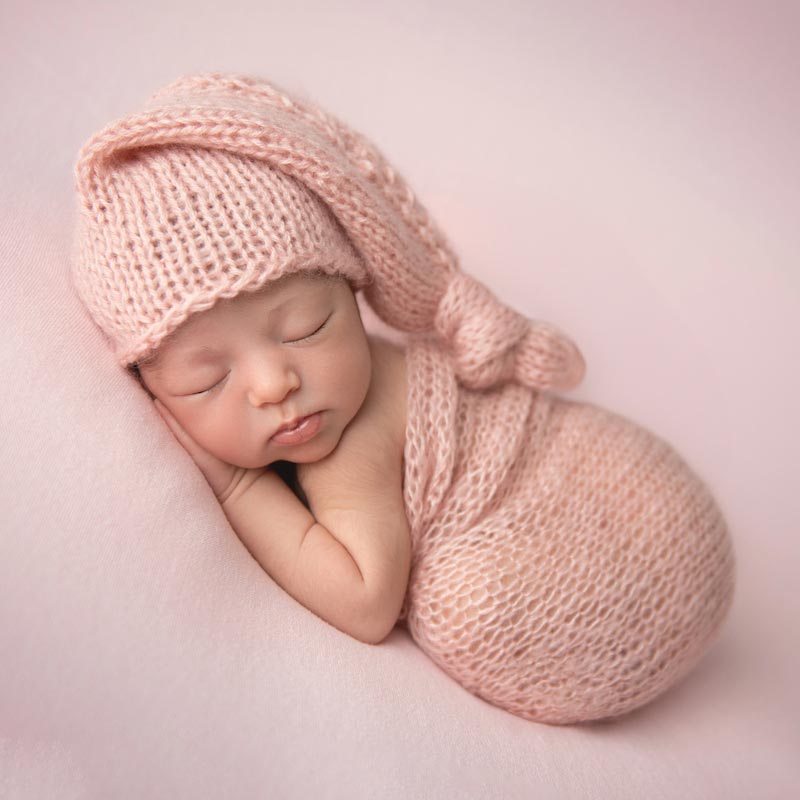 Sweet cuddly newborn baby swaddled in pink