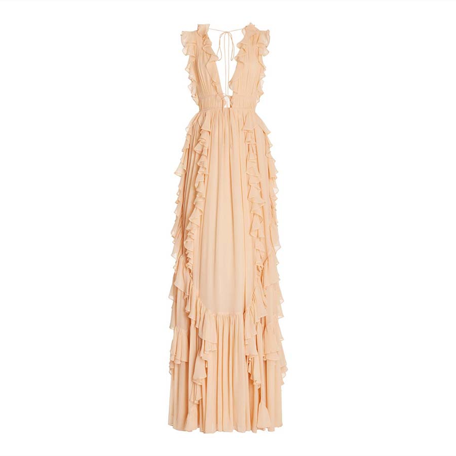 A long, peach-colored gown with a deep V-neckline. The dress features a series of ruffles cascading down the front and sides, adding a flowy and elegant look. It has a sleeveless design and a tie detail at the back neck.